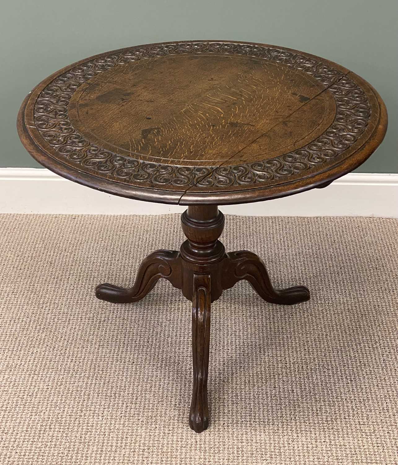 19th century oak tripod table, circular tilt top carved with a band of scrolls within a moulded 19th century oak tripod table, circular tilt top carved with a band of scrolls within a moulded